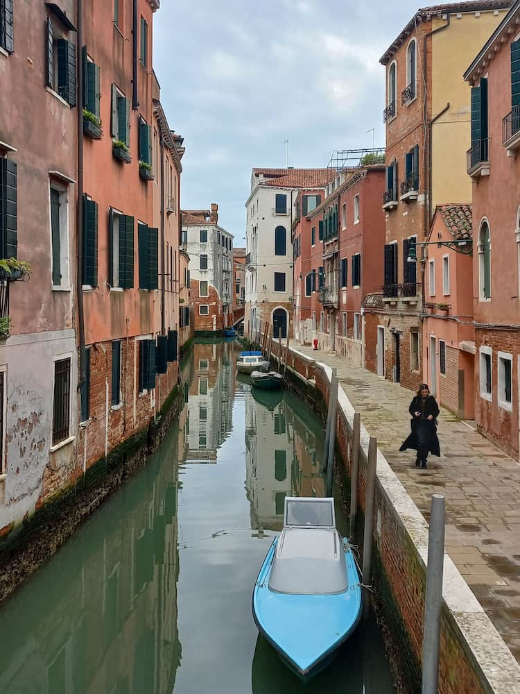 Una ragazza cammina per una calle tranquilla lungo il canale 