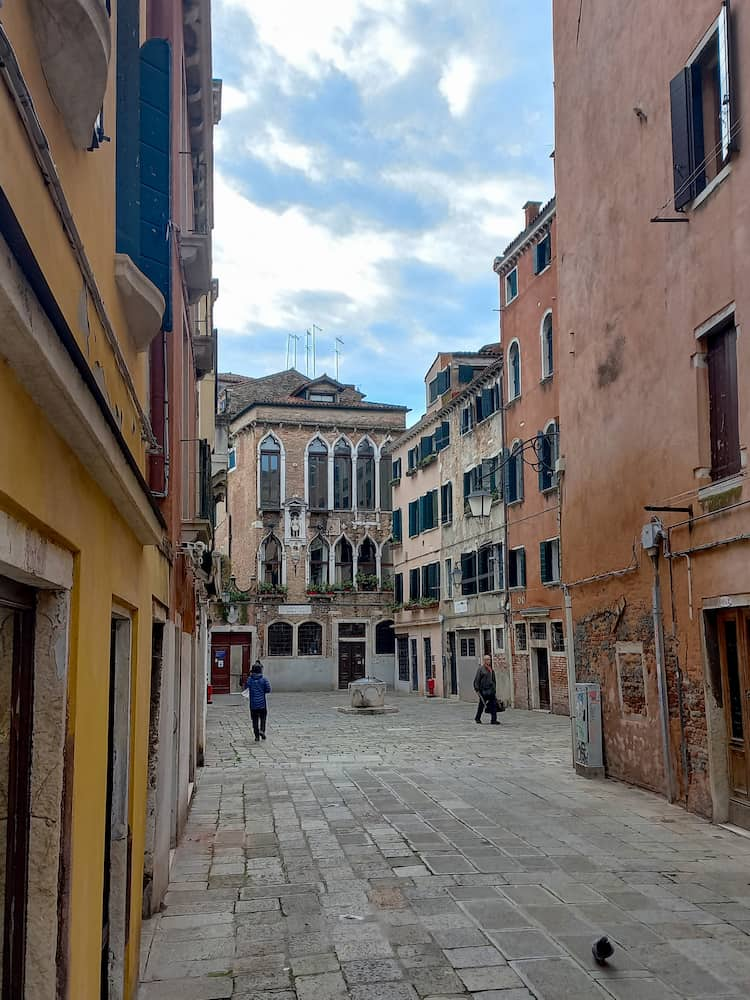 Un piccolo campo con sul fondo un palazzo dalle finestre decorate