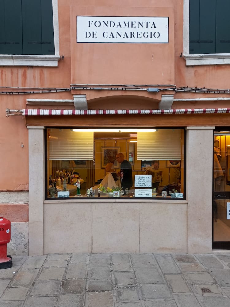 La scritta sestiere di Cannaregio sul muro, con sotto il negozio di un barbiere 